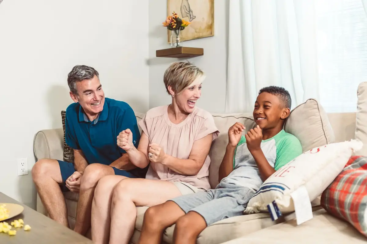 A family laughing together on a living room couch